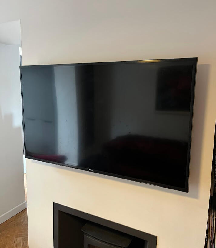TV mounted on wall above wood burner